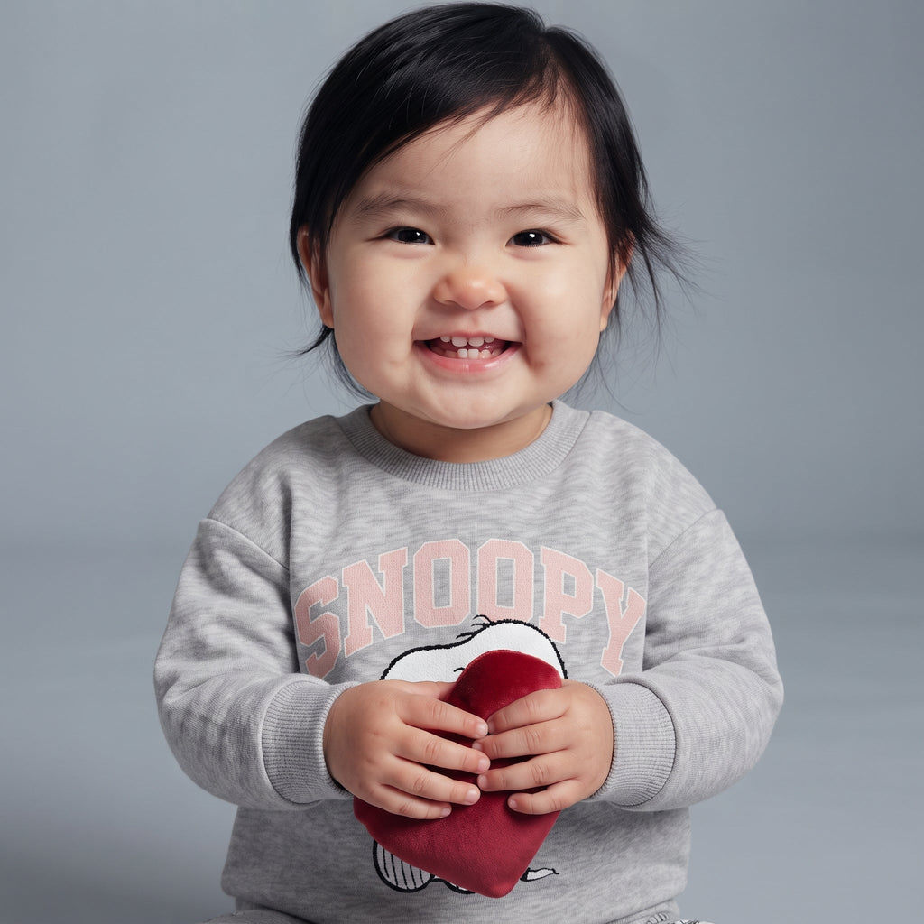 Bebé sonriente vistiendo sudadera gris EmpiBy con estampado de Snoopy y corazón rojo, estilo tierno y cómodo