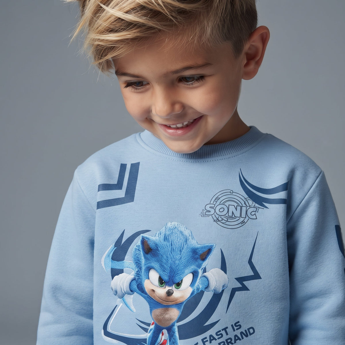 Niño sonriente vistiendo sudadera azul claro de Sonic de EmpiBy con estampado dinámico y cuello redondo