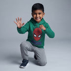 Niño sonriente con sudadera verde de Spider-Man y pantalón jogger gris de EmpiBy en pose de acción