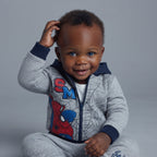 Bebé sonriente con sudadera EmpiBy de Spiderman gris y azul, con capucha y cierre frontal, estilo jogger cómodo.