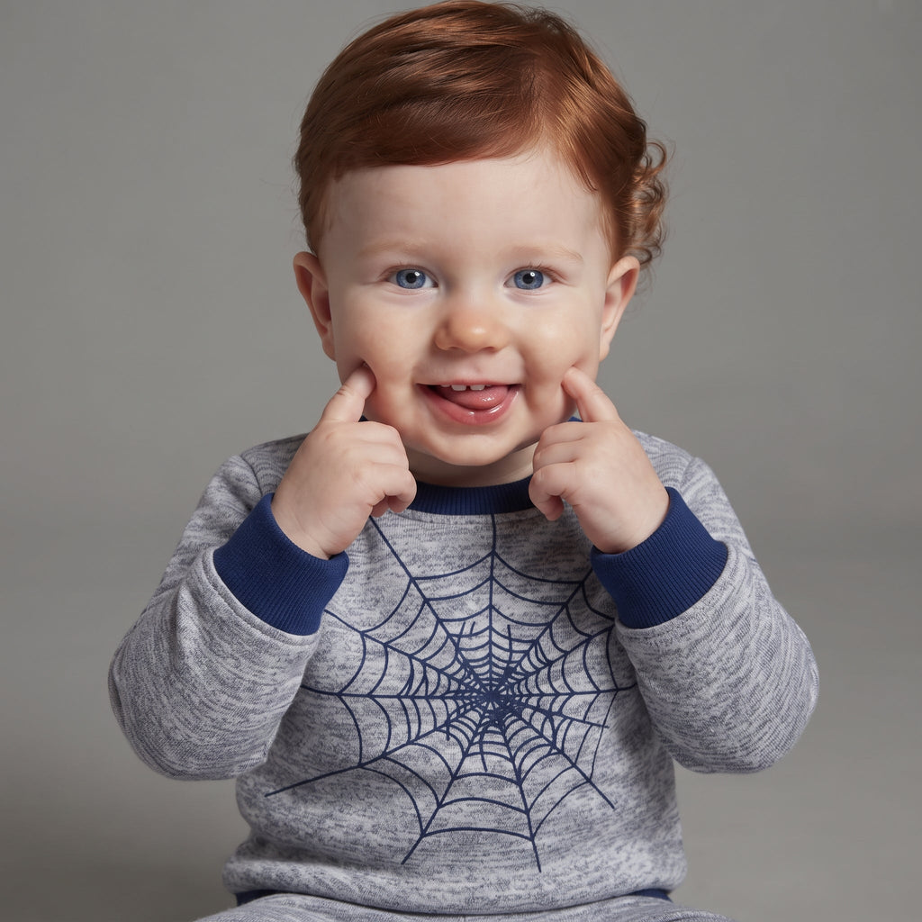Bebé pelirrojo sonriente vistiendo sudadera gris EmpiBy con estampado de telaraña de Spider-Man y detalles azules
