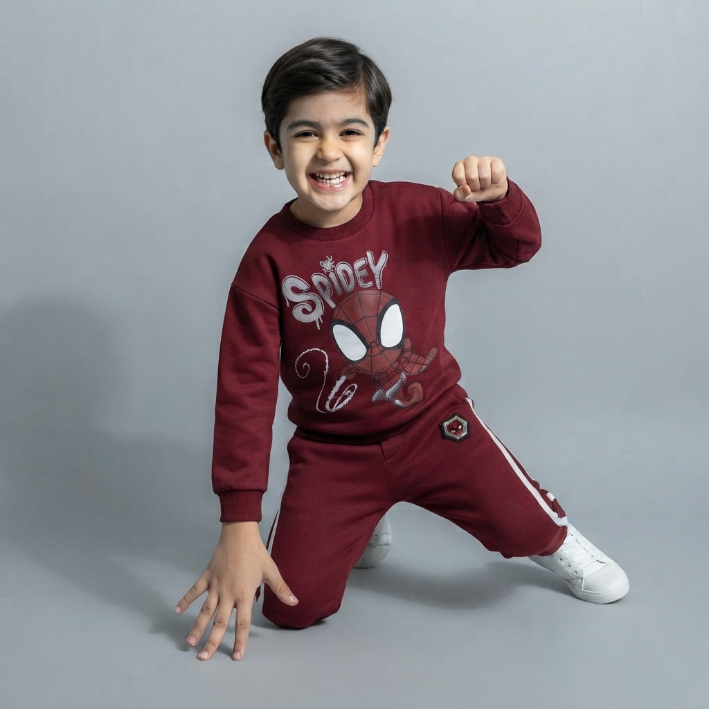 Niño sonriente vistiendo conjunto EmpiBy de sudadera y pantalón color burdeos con estampado de Spidey estilo urbano