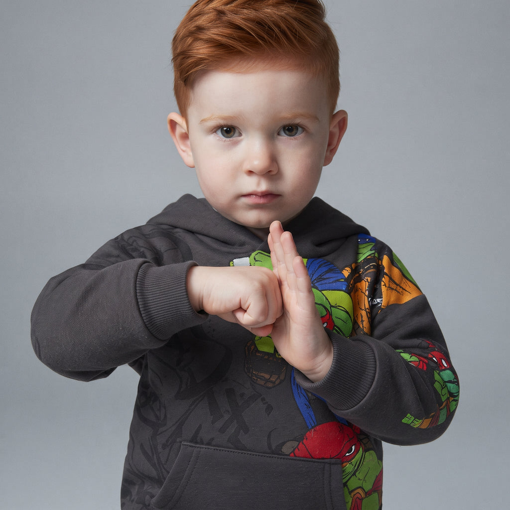 Niño con sudadera gris EmpiBy de las Tortugas Ninja con estampado gráfico y capucha, estilo urbano y cómodo.