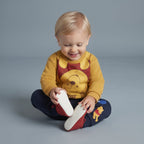Bebé sonriente con conjunto EmpiBy de Winnie Pooh: buzo amarillo y pantalón jogger azul marino con estampado.