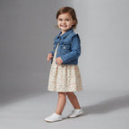 Niña pequeña sonriendo con vestido floral y chaqueta de mezclilla EmpiBy, conjunto cómodo de algodón y denim suave.